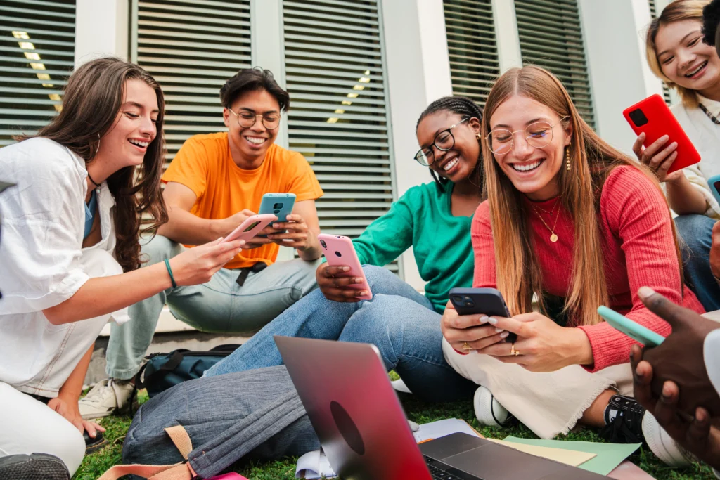 As telas ocupam o centro das atenções e das interações entre os estudantes, refletindo como a digitalização e a hiperconectividade redefinem os processos de aprendizagem.